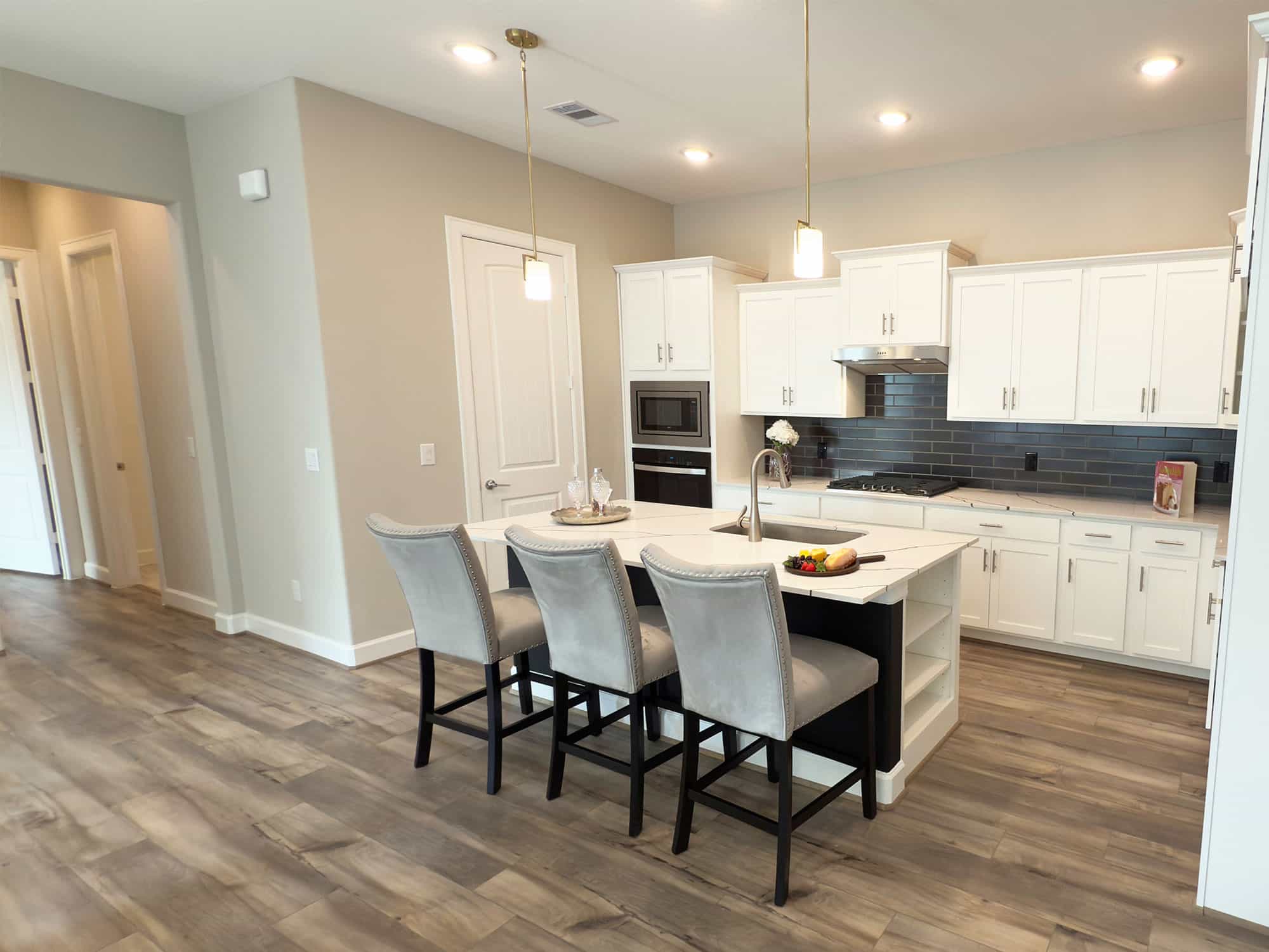 Promenade III open kitchen with island seating and white cabinets at 1214 Hidden Oaks Dr