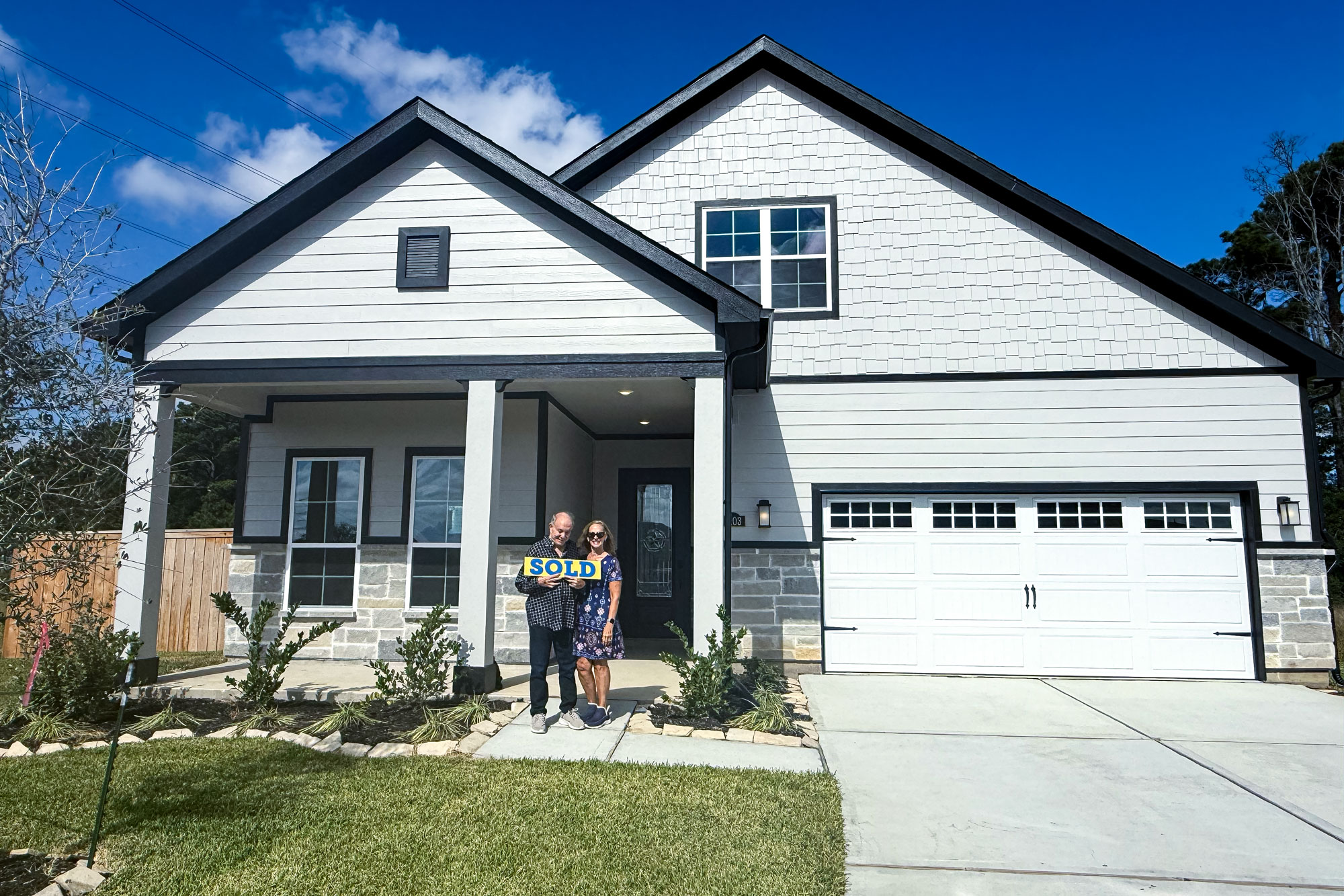 New homeowners standing in front of their single-story home at Winfrey Estates